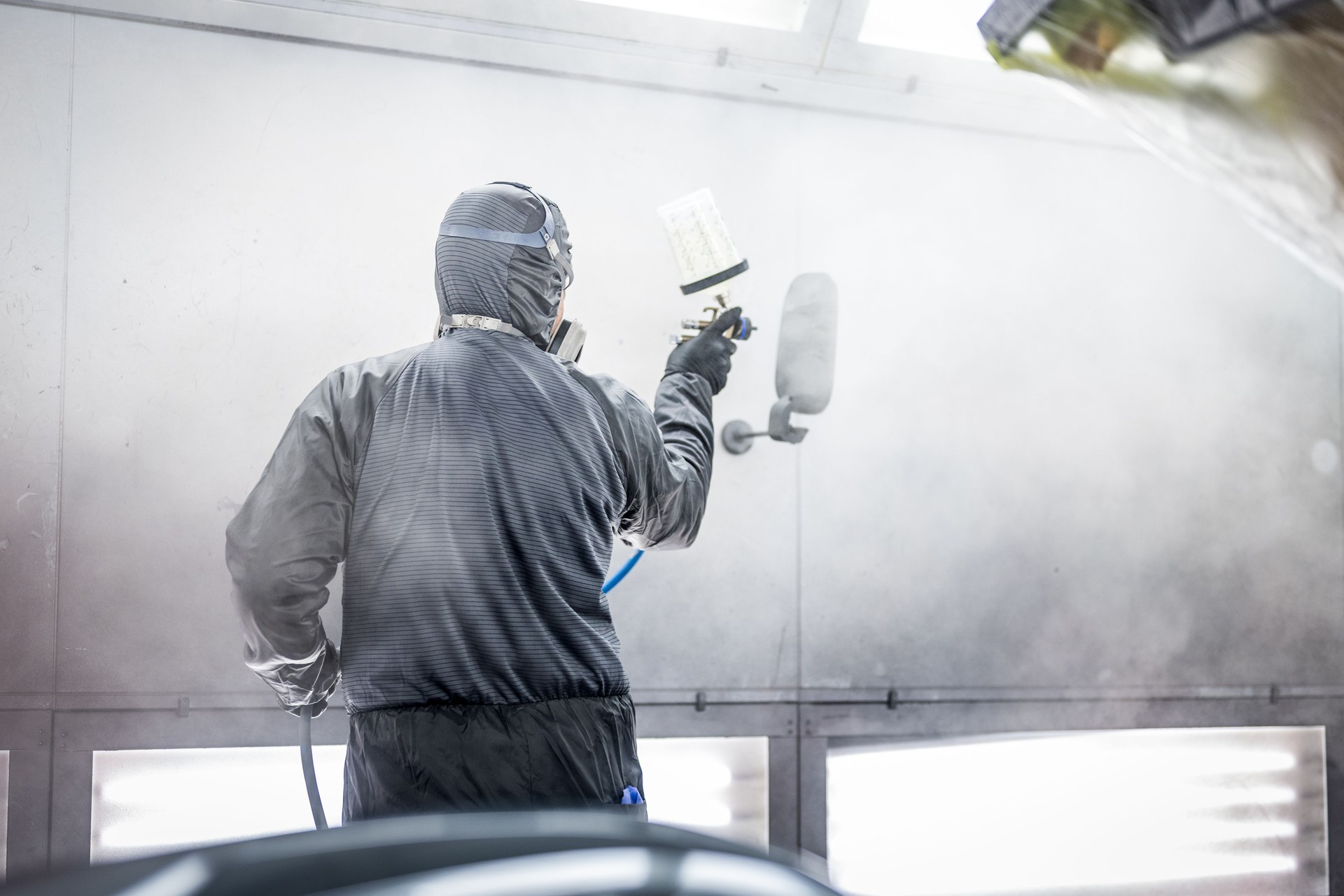 Skilled Caucasian Male Spray Painting Car Parts in Workshop