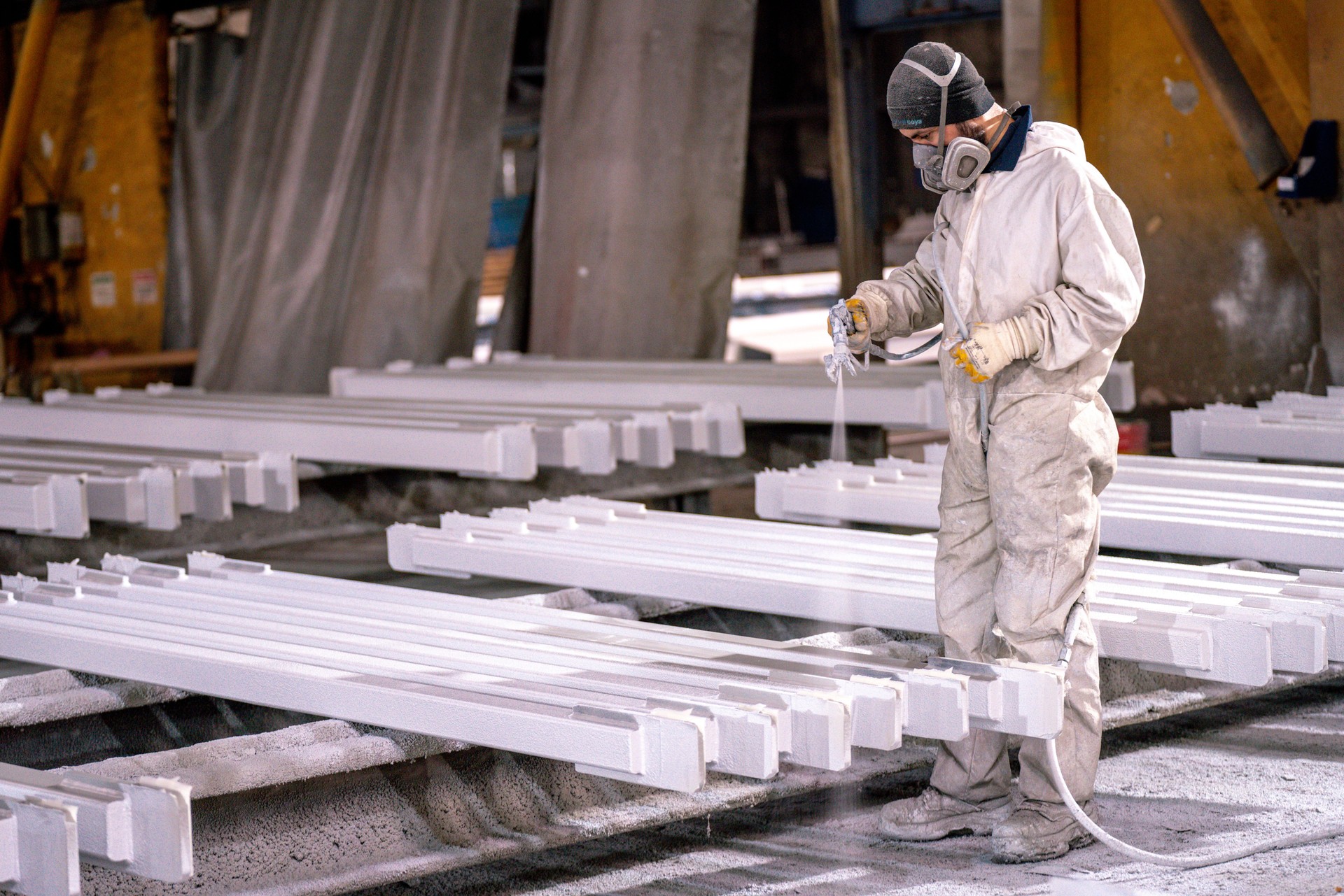 Man painting metal in factory